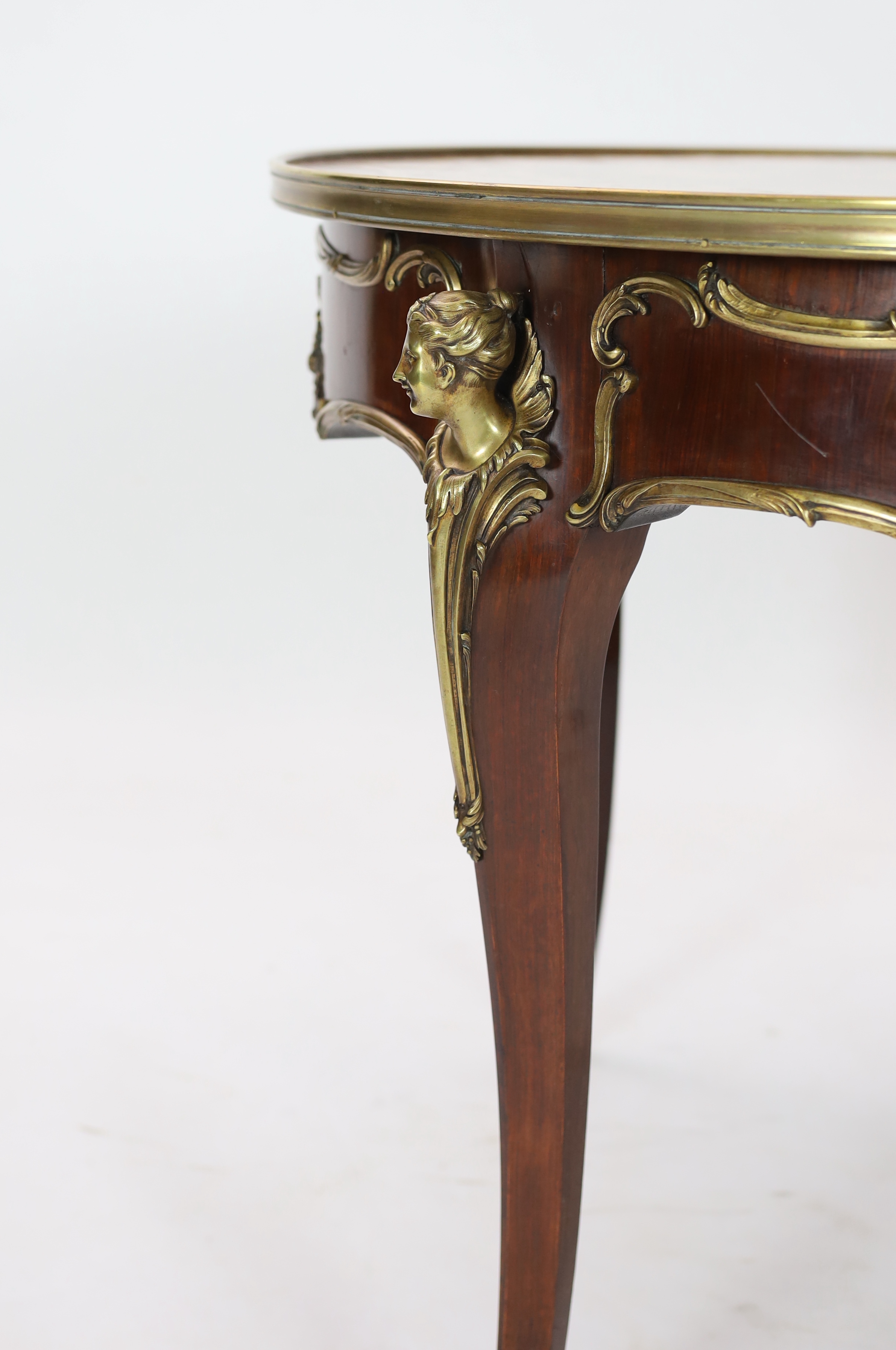 A Louis XVI style ormolu mounted marquetry centre table, decorated with musical, agricultural and arts related trophies within a band of flowers, the circular top over a scroll mounted frieze with classical mask headed c